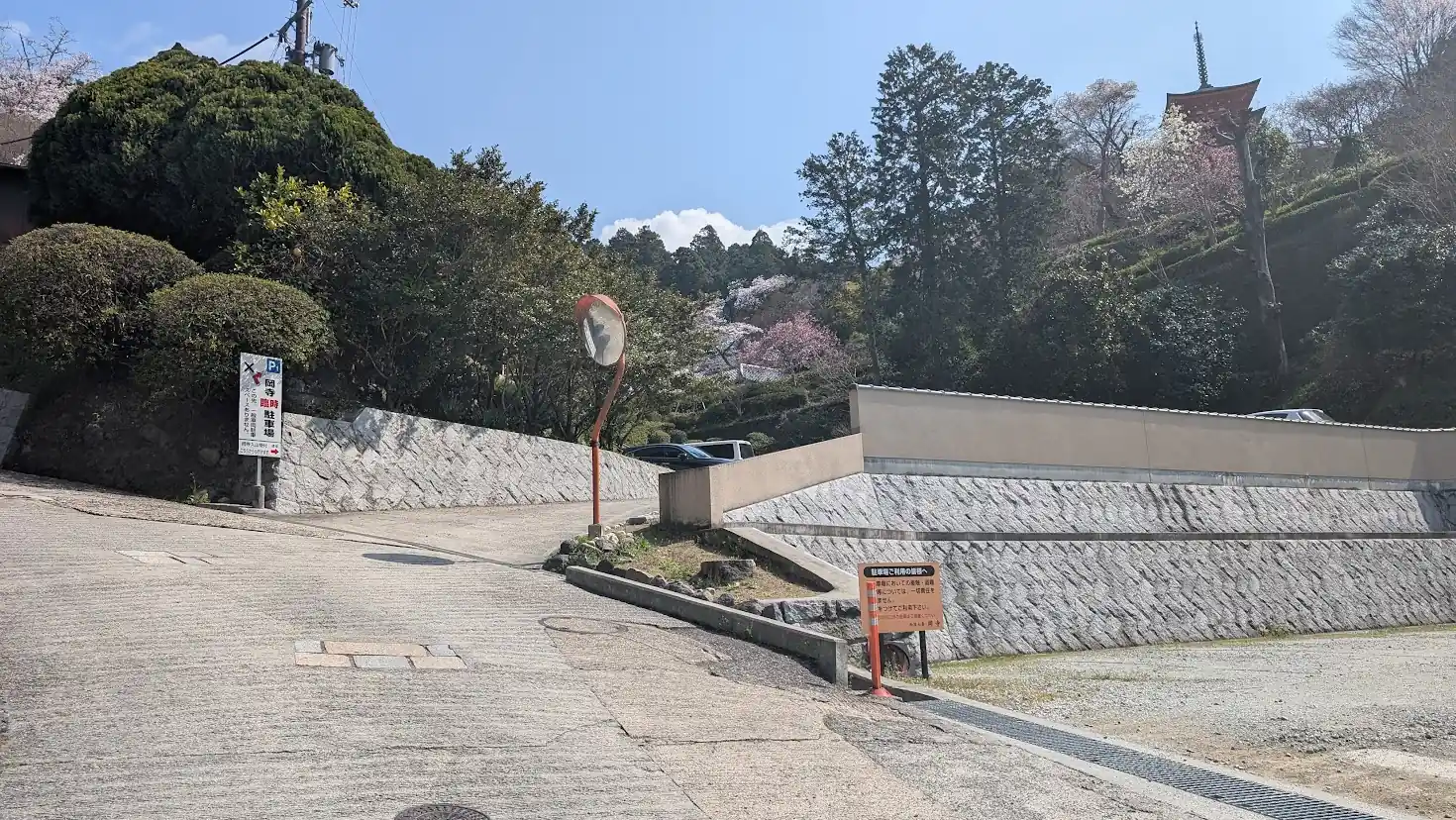 岡寺の仁王門のすぐ横にある、無料駐車場への坂道入口。案内看板とカーブミラーがある風景