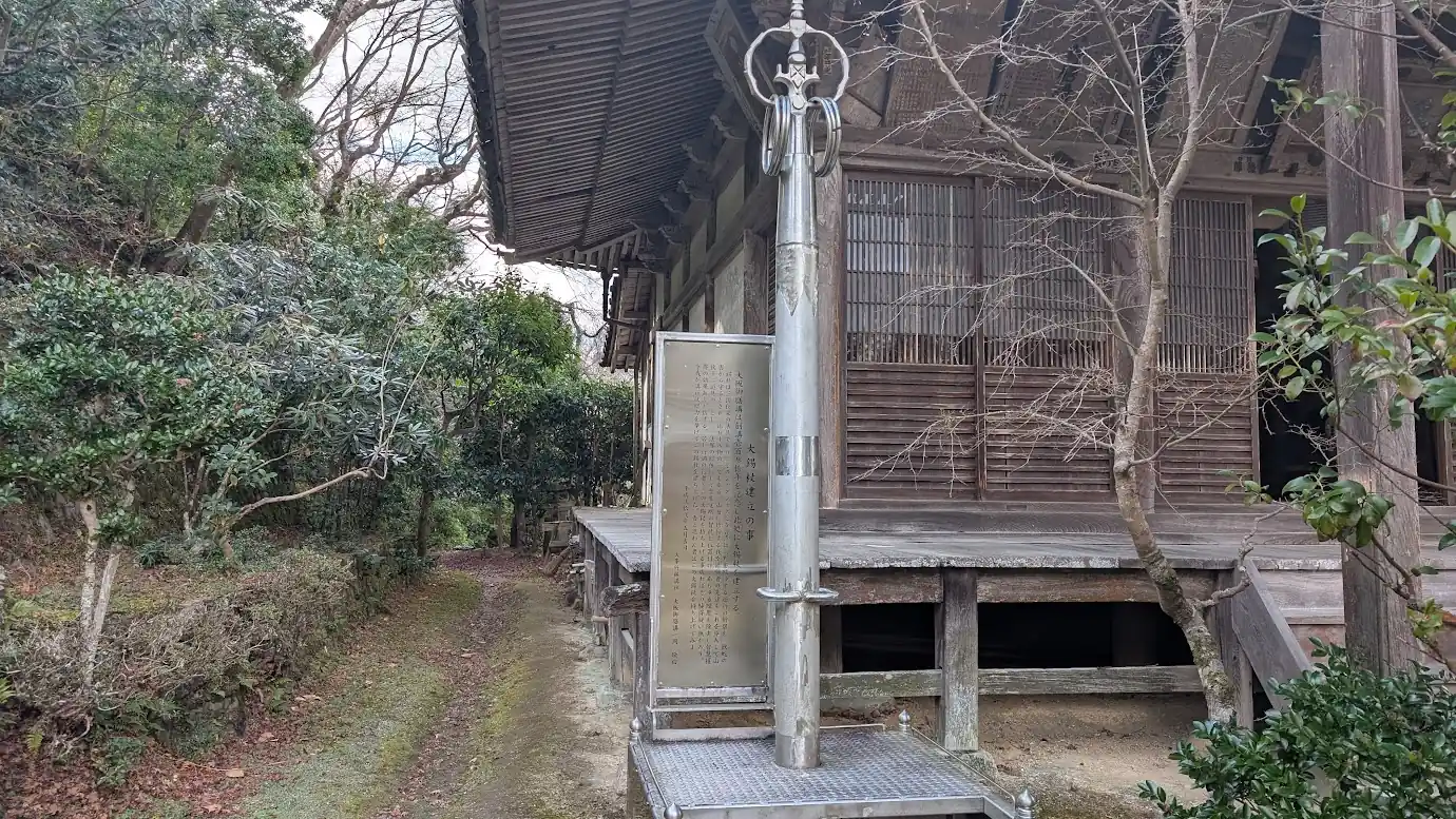 竹林院の本堂前に建立された、銀色に光る巨大な「大錫杖（だいしゃくじょう）」と、その由来が刻まれた金属製の案内板