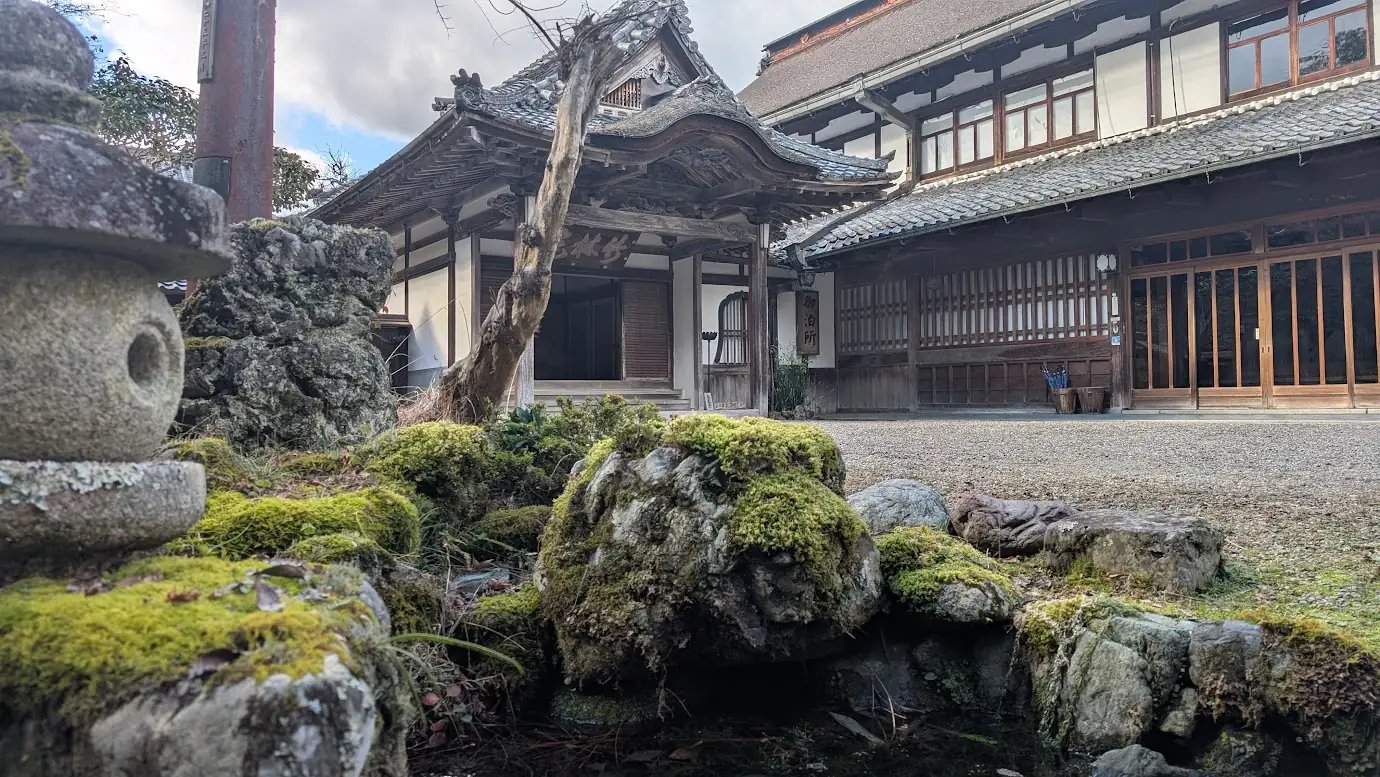 吉野山の由緒ある宿坊「竹林院群芳園」の趣深い宿泊棟と、手前に広がる美しい苔をまとった庭石と池