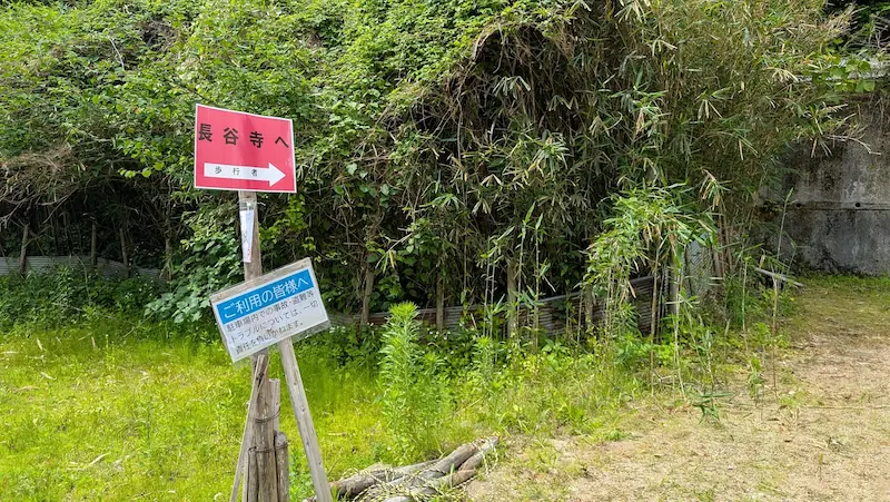長谷寺へ向かう歩行者用の赤い案内看板と、免責事項が記載された青い看板。