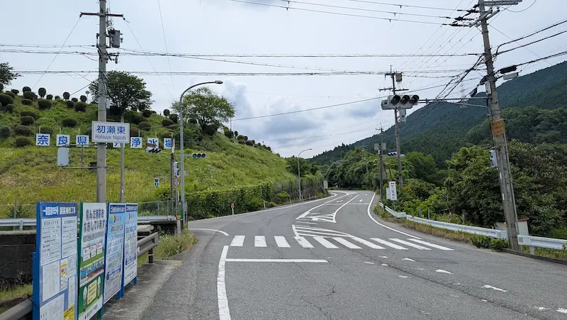 長谷寺参拝の目印となる「初瀬東」交差点。緩やかなカーブと周辺の緑が広がる道路風景。