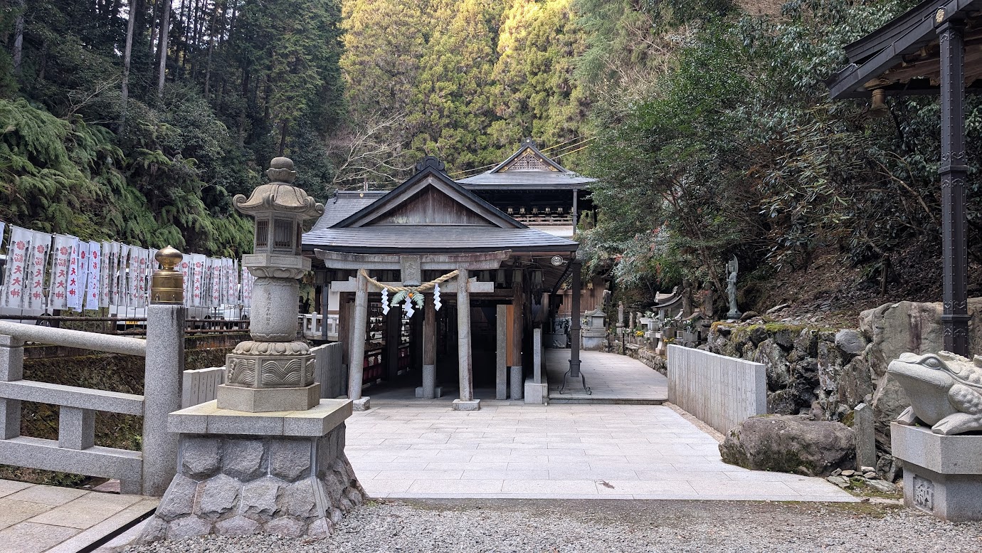 深い吉野の森に包まれた脳天大神の本堂(全体像)。手前に立派な石灯籠と鳥居があり、奥へと続く厳かな木造建築の風景。