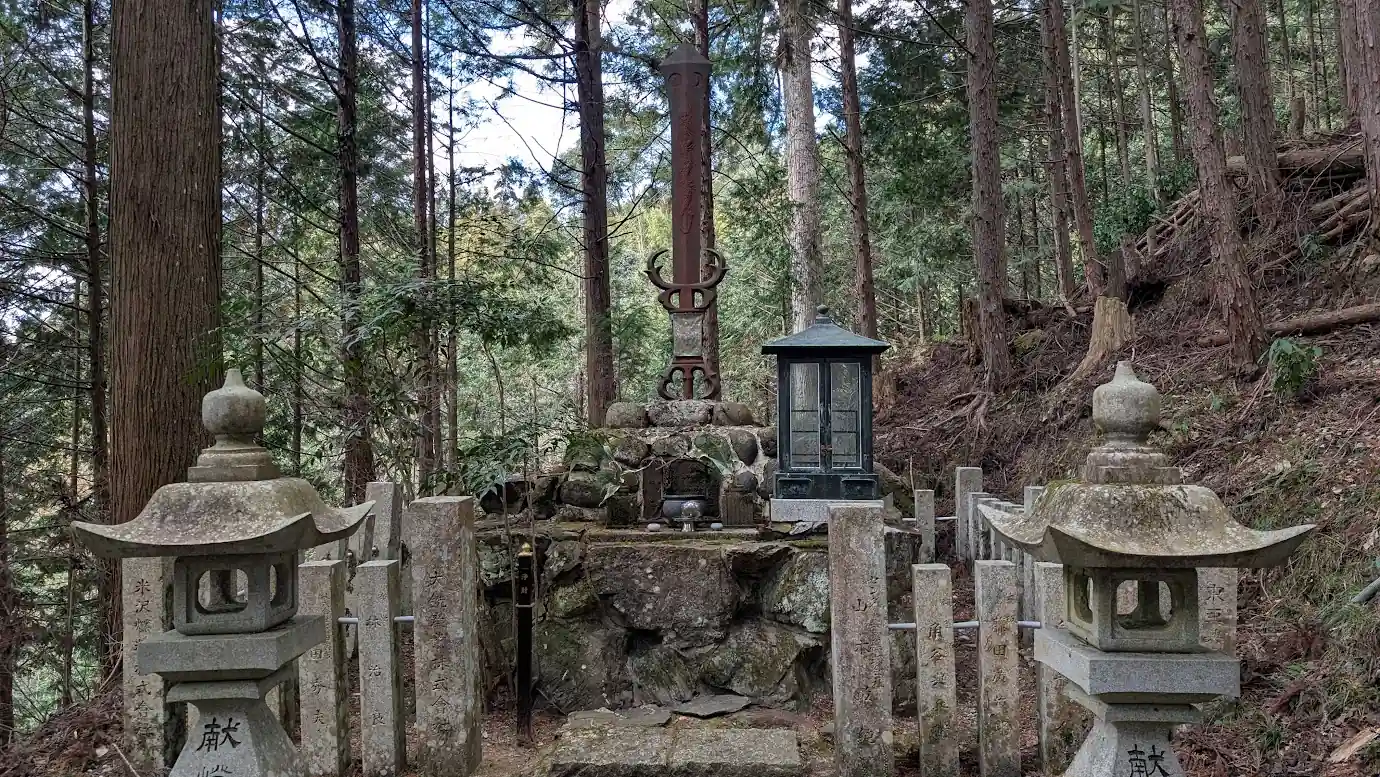 脳天大神へと続く石段の道中にある、龍が巻き付いた巨大な剣のモニュメント「倶利伽羅剣(くりからけん)」。深い杉木立の中で石垣の上に祀られている神秘的な風景。
