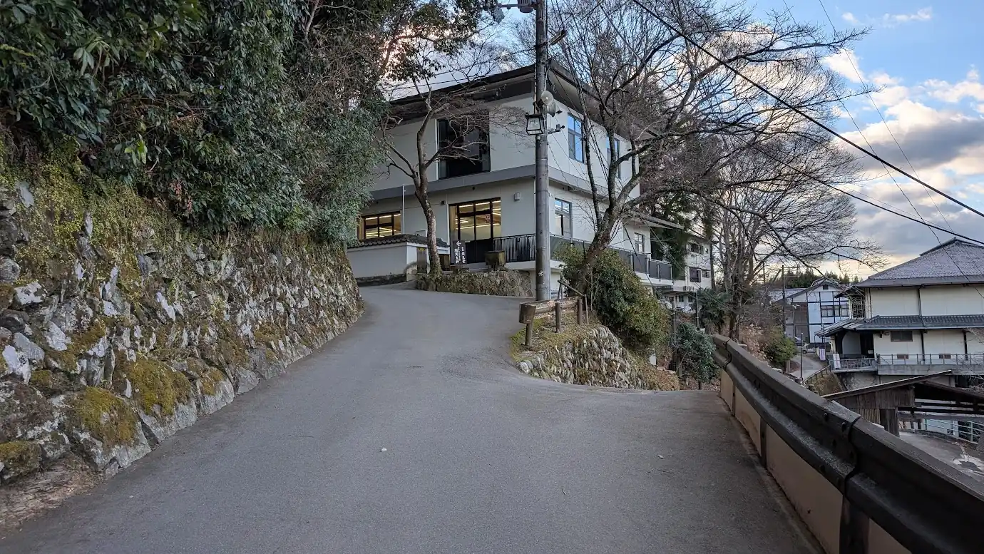 金峯山寺の駐車場へ続く道にある最後の分岐点。左の石垣沿いの上り坂は本堂横の駐車スペースへ、右奥へ続く道はメイン駐車場（旧・吉野小学校跡地）へと繋がっている。