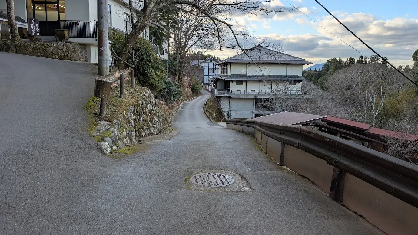 金峯山寺のメイン駐車場（旧・吉野小学校跡地）へと続く右側のルート。ガードレール沿いに続く、少し道幅が狭くなった舗装路の風景。
