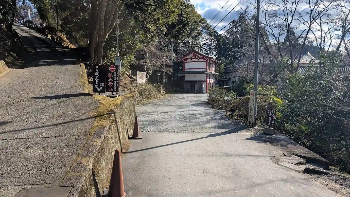 金峯山寺本堂（蔵王堂）のすぐ横にある、冬の閑散期限定で開放される未舗装・線引きなしの砂利の駐車スペースへの入り口