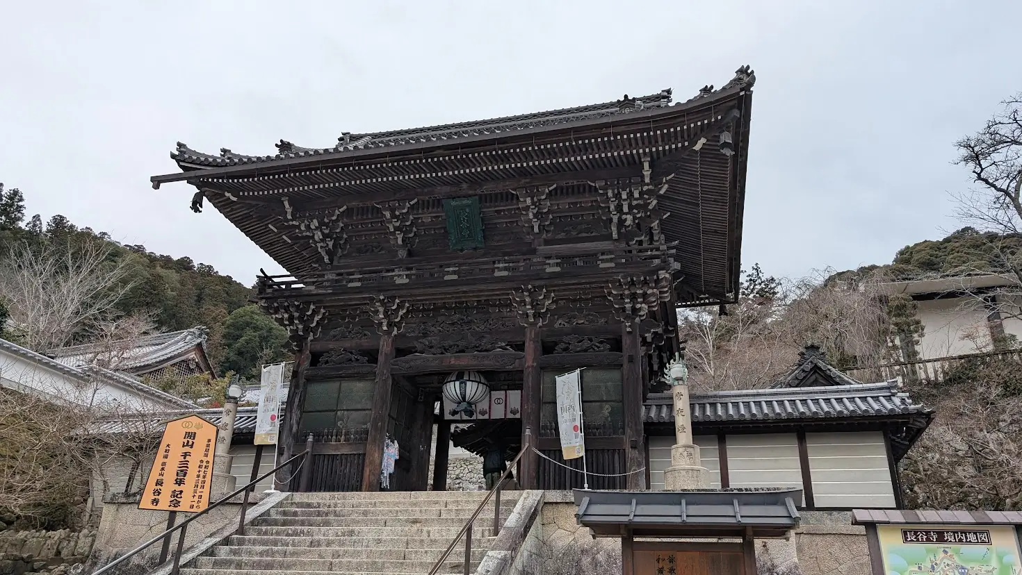 奈良県桜井市・長谷寺の正門である重要文化財「仁王門」。重厚な二重門の構造で、手前には石段があり、左右には灯籠と「開山一三〇〇年記念」の看板が立っている。