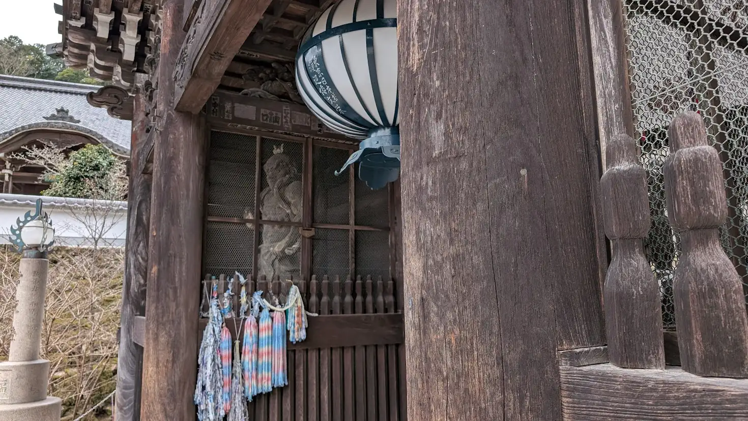 長谷寺・仁王門の左側に安置された仁王像（吽形）。口を固く結び、内に秘めた力を感じさせる表情。背景には冬の初瀬山の斜面が広がっている。