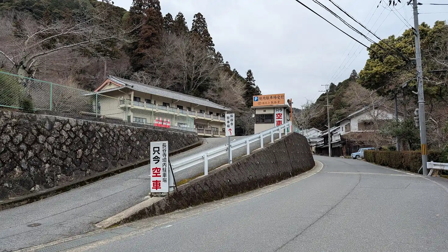 長谷寺の境内駐車場へと続く上り坂の入口。看板には「長谷寺境内駐車場 只今空車」と大きく書かれており、奥には受付の建物が見える。