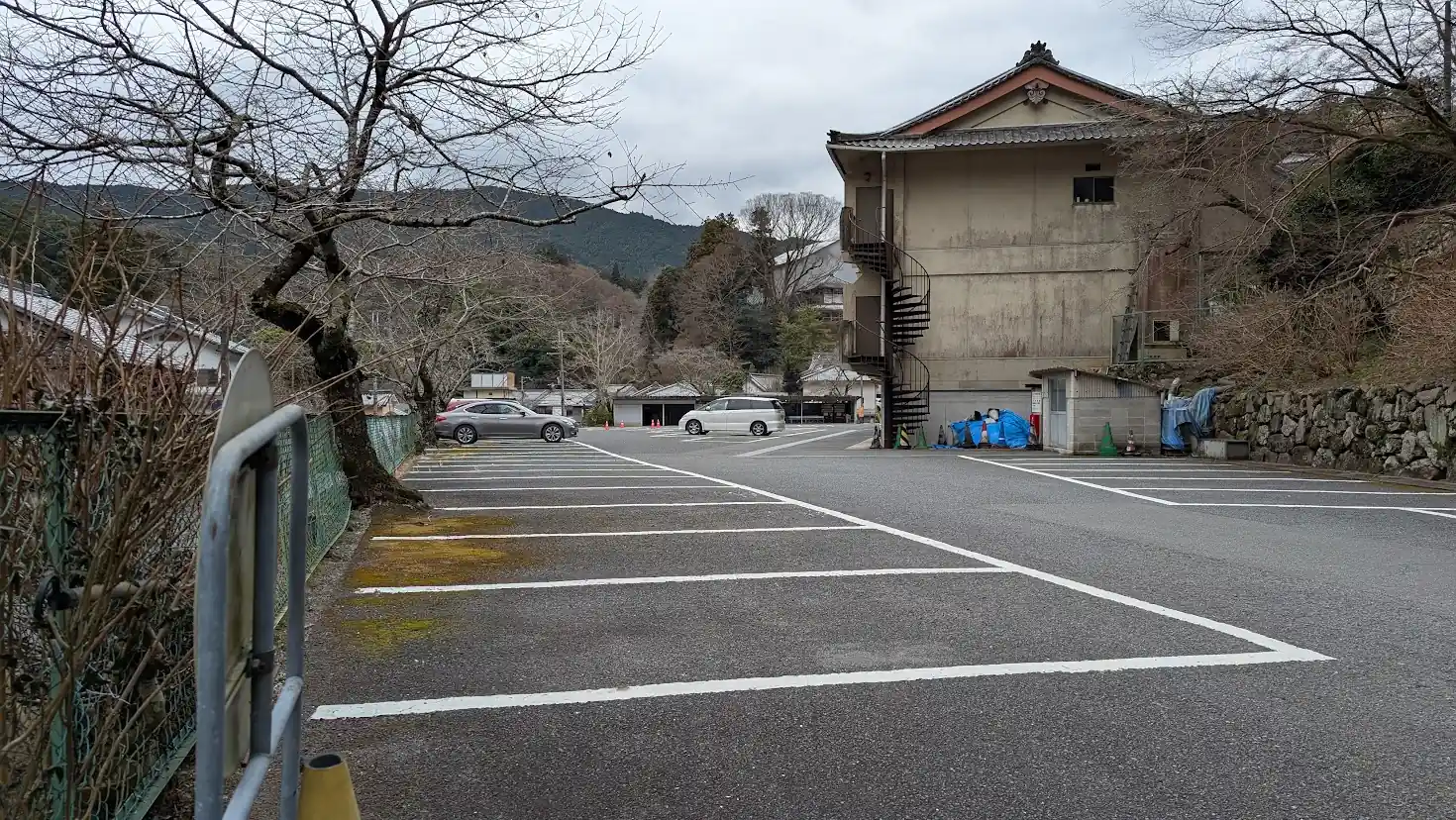 長谷寺境内駐車場の内部。白線で区切られた広い舗装済みの駐車スペースが広がり、奥にはお寺の建物や冬の山々が写っている。