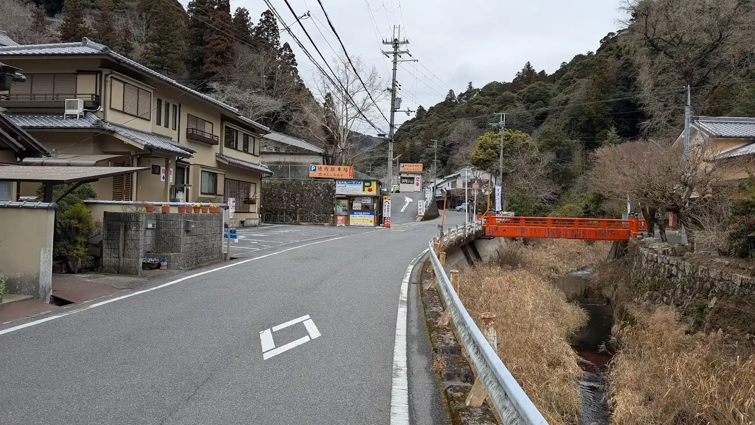 長谷寺に最も近い民間駐車場の一つ。看板には「1時間400円・1日最大500円」と料金が記載されており、背景には門前町へと続く道と赤い橋（初瀬橋）、初瀬川が写っている。