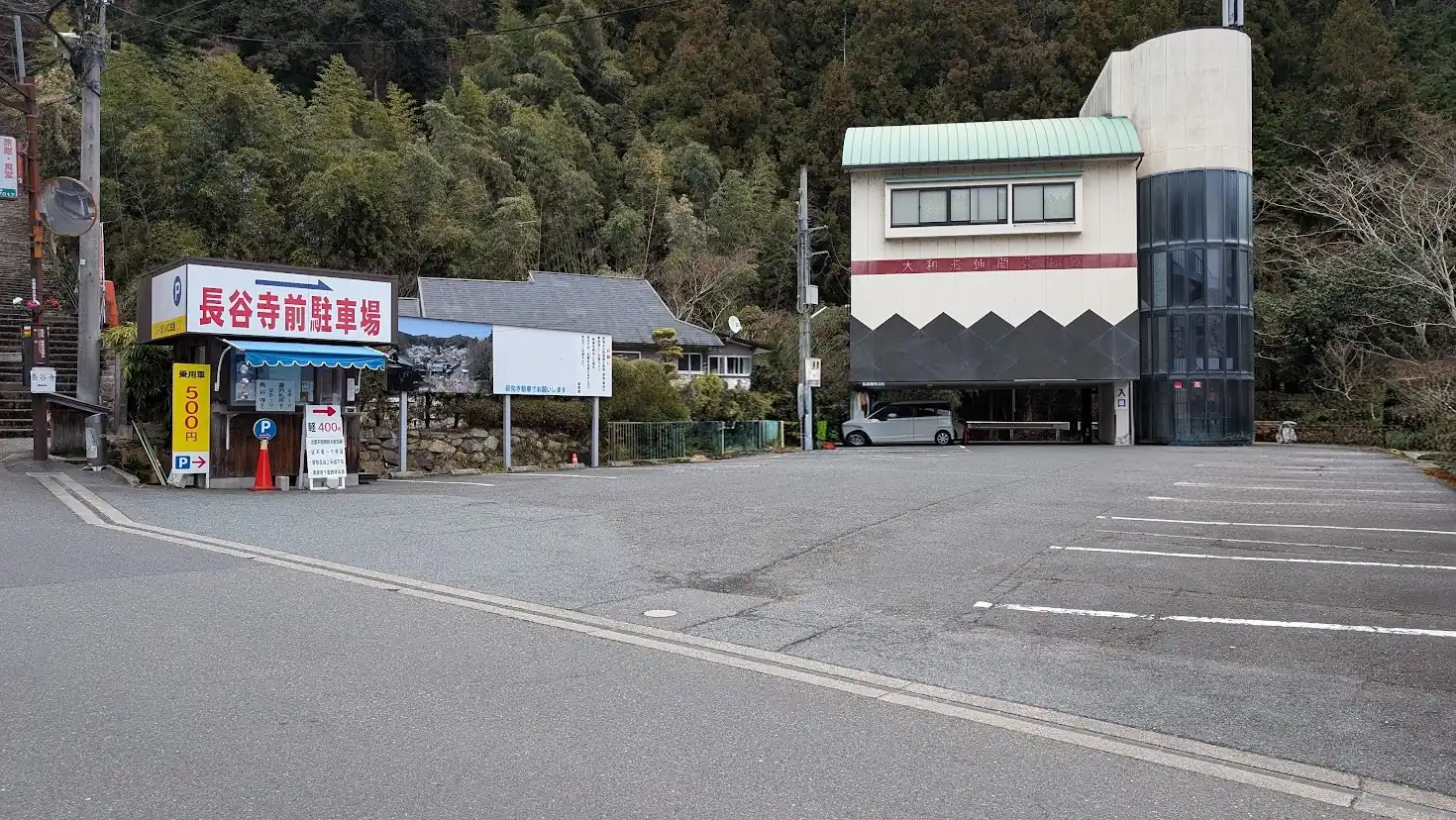 長谷寺のすぐ門前にある「長谷寺前駐車場」。看板には「軽用 400円」「普通車 500円」と大きく料金が記載されており、背景には白線が引かれた広い駐車スペースがある風景。