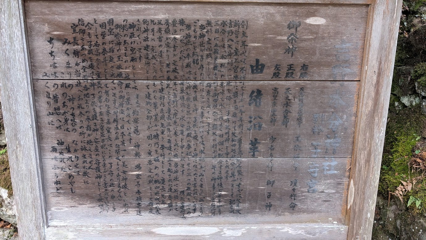 奈良県吉野町、世界遺産・吉野水分神社の境内に立つ木製の由緒書き看板。御祭神（天之水分神など）や由緒沿革が詳しく記されており、豊臣秀頼による慶長9年の再建についても言及されている。古い木肌に墨書きされた歴史解説（2026年1月撮影）。