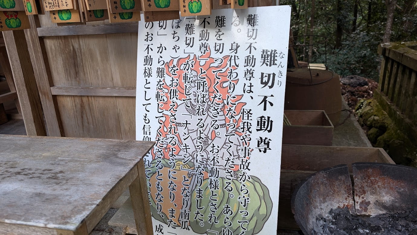 奈良県吉野町、如意輪寺の難切不動尊前にある案内板。不動明王のイラストと共に、「難切(なんきり)」が転じて「ナンキン(南瓜)」をお供えするようになった由来や、怪我・事故から身代わりになって守ってくれる功徳が記されている(2026年1月撮影)。