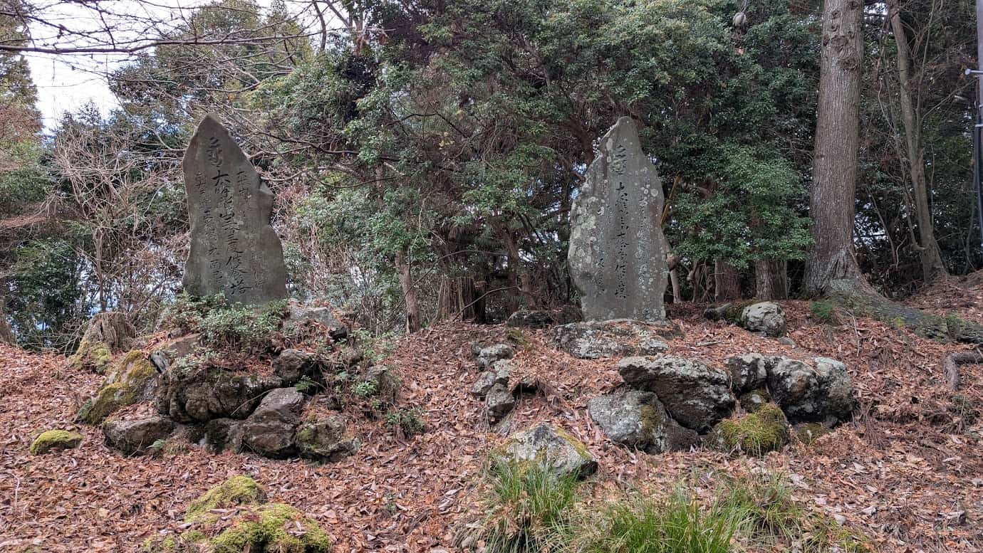 吉野山の道沿い、枯れ葉が積もる斜面に立つ2基の大きな石碑。右側には「南無大師遍照金剛」と刻まれ、歴史の重みを感じさせる古びた質感(2026年1月撮影)。