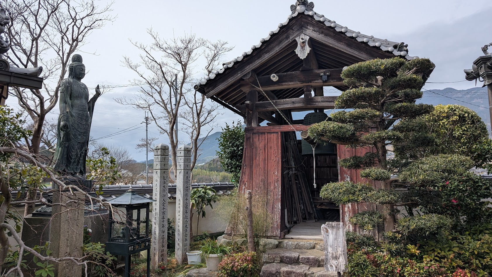奈良県御所市・弥勒寺の境内にある鐘楼と、その傍らに立つ慈光観音像の全体風景。