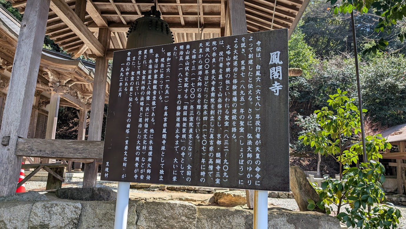 奈良県黒滝村の鳳閣寺にある解説板。白鳳時代に役行者が創建し、後に理源大師が再興した歴史や、国指定重要文化財の本堂、理源大師の廟塔について詳しく記されている。背景には鐘楼が見える。