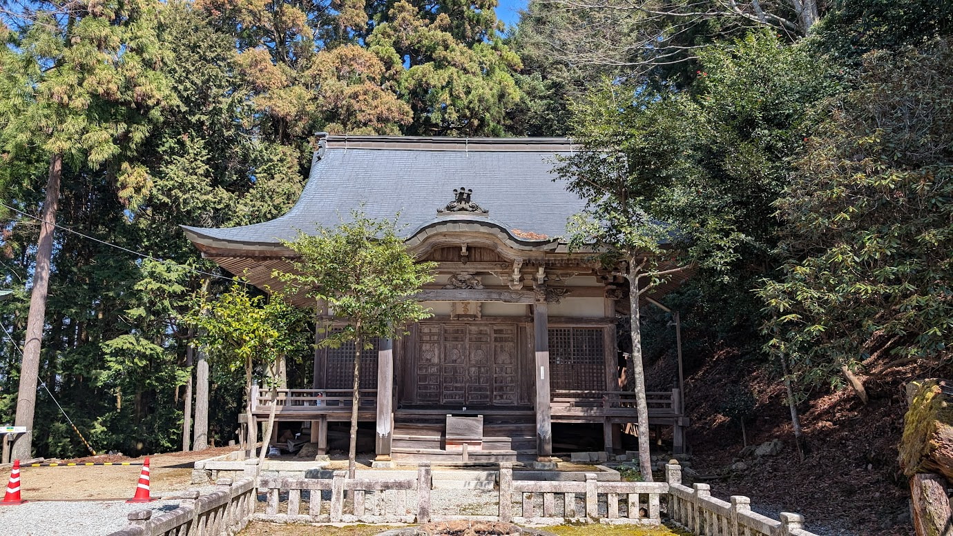 奈良県黒滝村にある鳳閣寺の本堂。入母屋造の重厚な木造建築で、屋根には優美な曲線がある。背後には鬱蒼とした杉林が広がり、手前には石の玉垣がある。