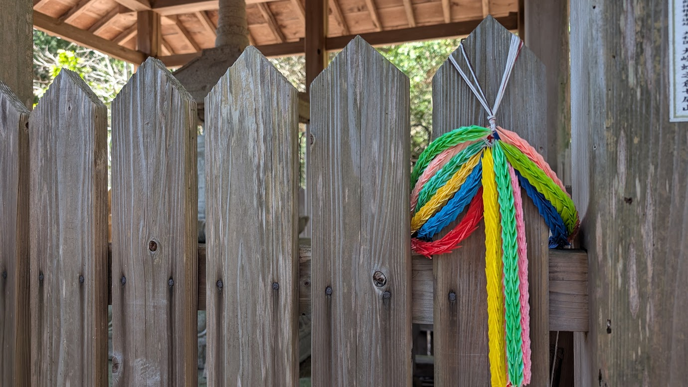 鳳閣寺の理源大師御廟（廟塔）を囲む木製の柵に掛けられた、色鮮やかな千羽鶴。背景には歴史を感じさせる木の柵と、御廟の屋根がわずかに見えている。