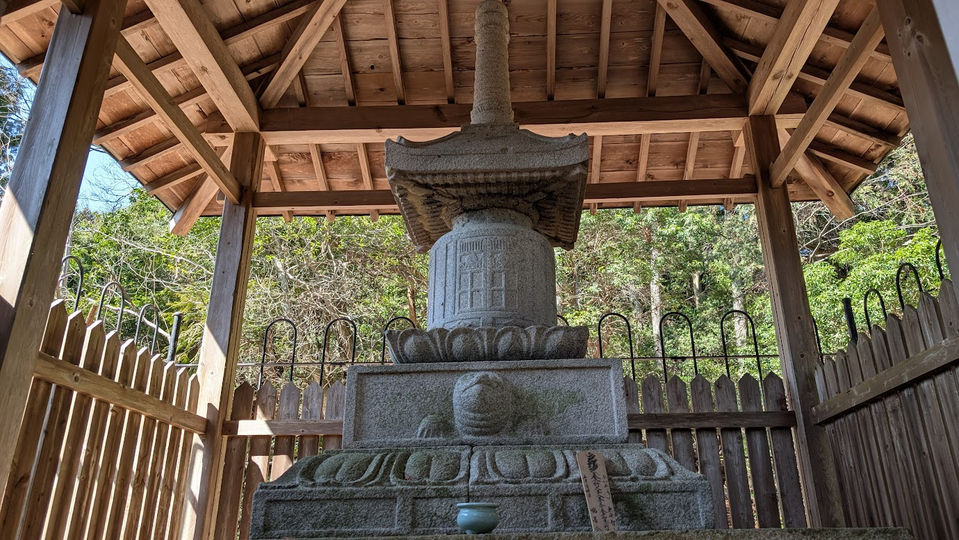 奈良県黒滝村、百貝岳の山中にある鳳閣寺の廟塔の全景。木造の覆屋に守られた石造十三重塔（国指定重要文化財）が、深い森に包まれて静かに佇んでいる。手前には苔むした石畳と石垣がある。