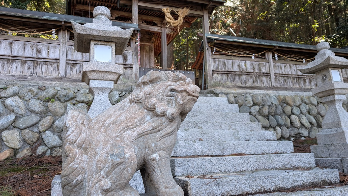 奈良県黒滝村の鳥住春日神社。苔むした境内に、石造りの狛犬（吽形）が鎮座し、奥に石段と木造の社殿が見える。木漏れ日が地面の苔を照らしている。