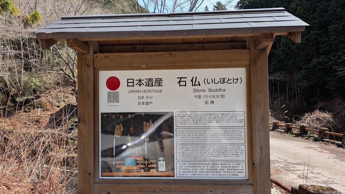 奈良県黒滝村にある日本遺産「石仏（いしぼとけ）」の解説看板。木製の屋根付き掲示板に、石仏の由来や写真、日本語・英語・韓国語・中国語での説明が書かれている。