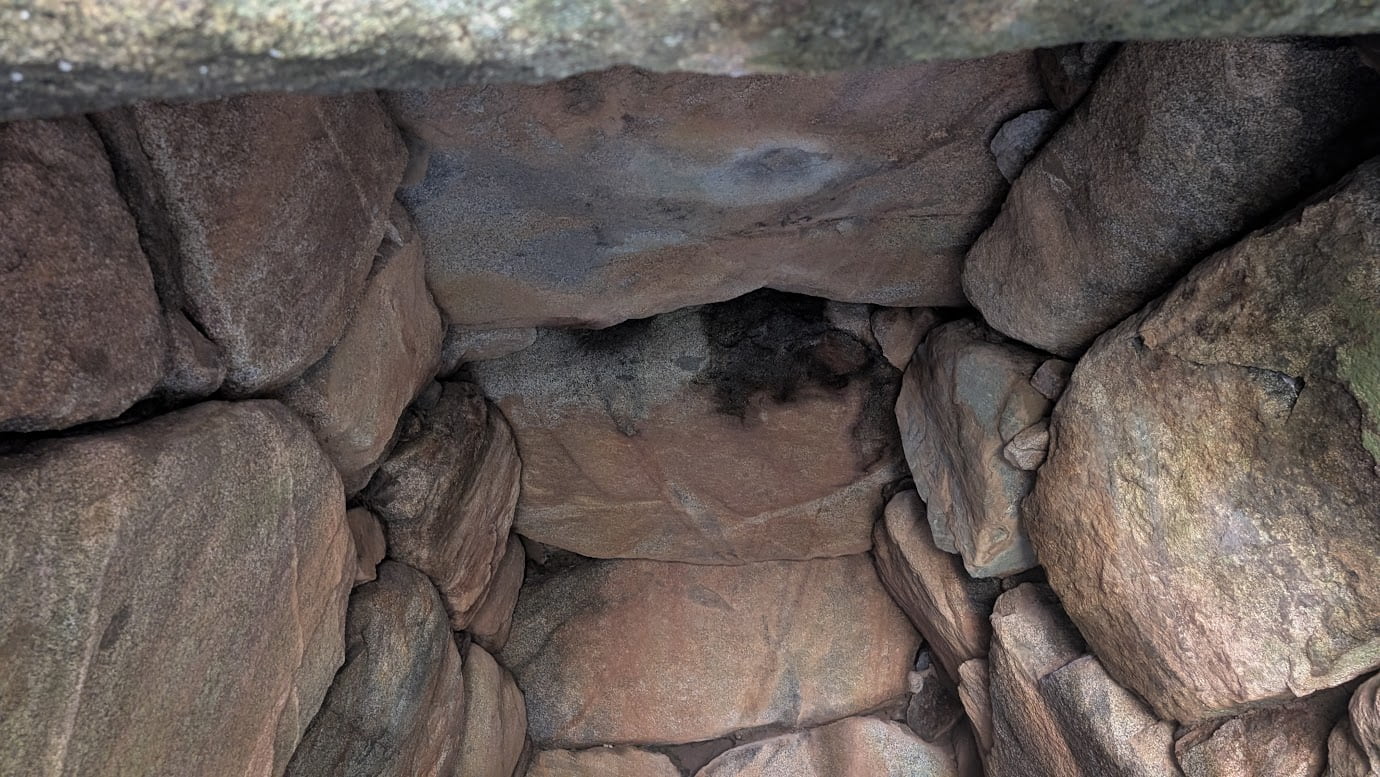 都塚古墳の石室内部から天井を見上げた様子。複数の巨大な岩がパズルのように組み合わさり、ドーム状に空間を覆っている。岩肌の荒々しい質感と、歴史の重みを感じさせる石組み。