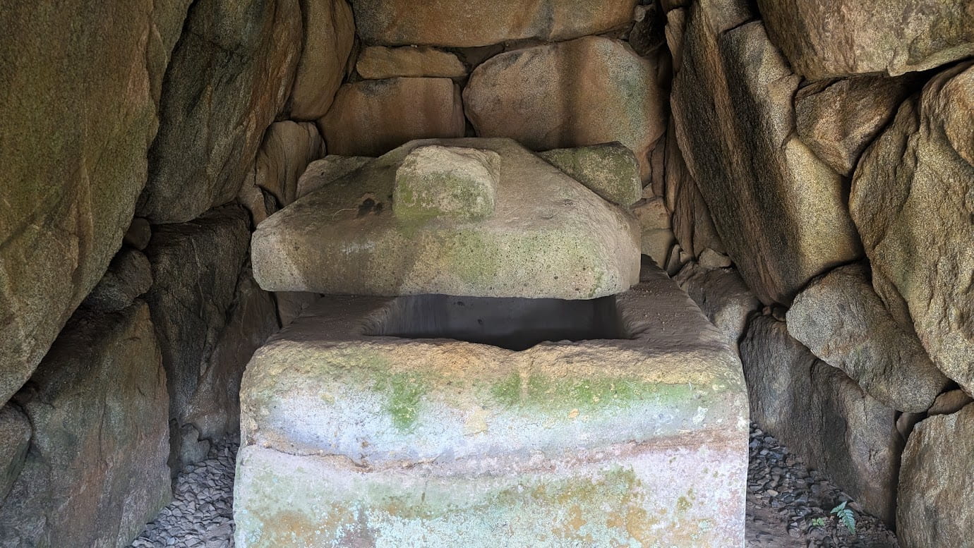 都塚古墳の石室内部。二上山産の凝灰岩で作られた「家形石棺」が置かれている。屋根のような形をした蓋(ふた)には突起(縄掛突起)があり、側壁の荒々しい石組みに囲まれた、1400年前のままのような静かな空間。