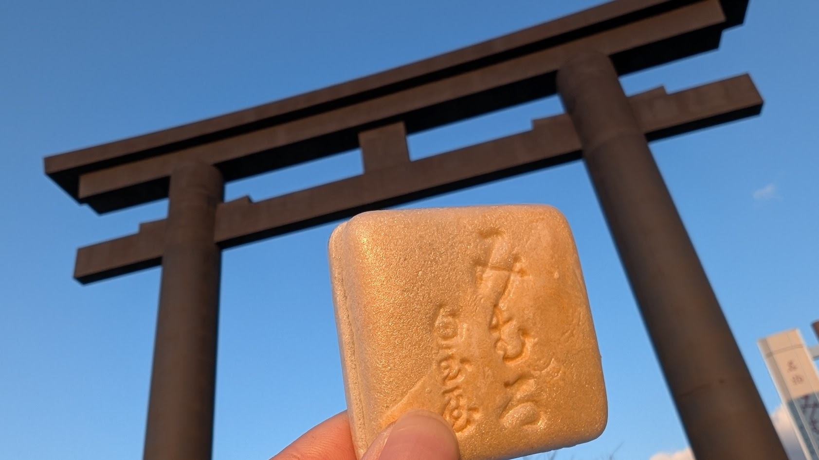 奈良県桜井市・大神神社の巨大な大鳥居を背景に、三輪名物の「みむろ最中」を添えた風景。