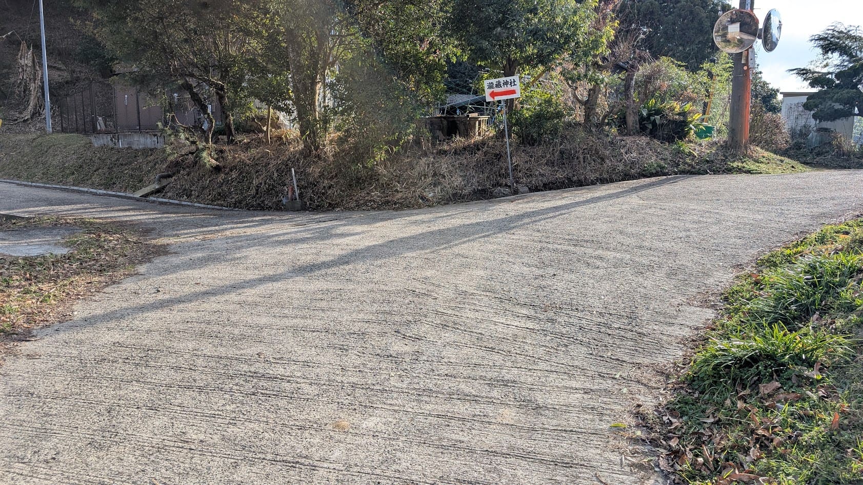 瀧蔵神社の境内に至る最後の分岐点。山道の脇に設置された「瀧蔵神社」を指し示す矢印の案内板と、急勾配の参道へと続く景観。
