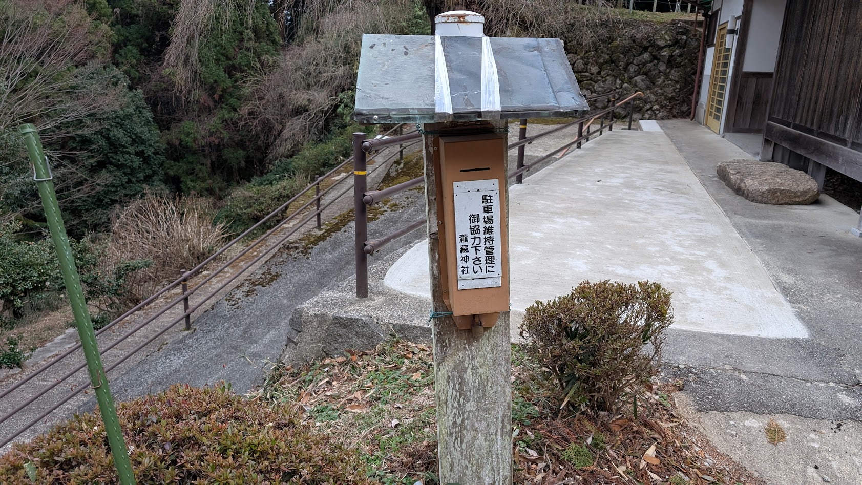 瀧蔵神社の駐車場にある、「駐車料金はお気持ち」と書かれた小さな看板と、維持管理協力金を入れるための小さなお金入れ箱。