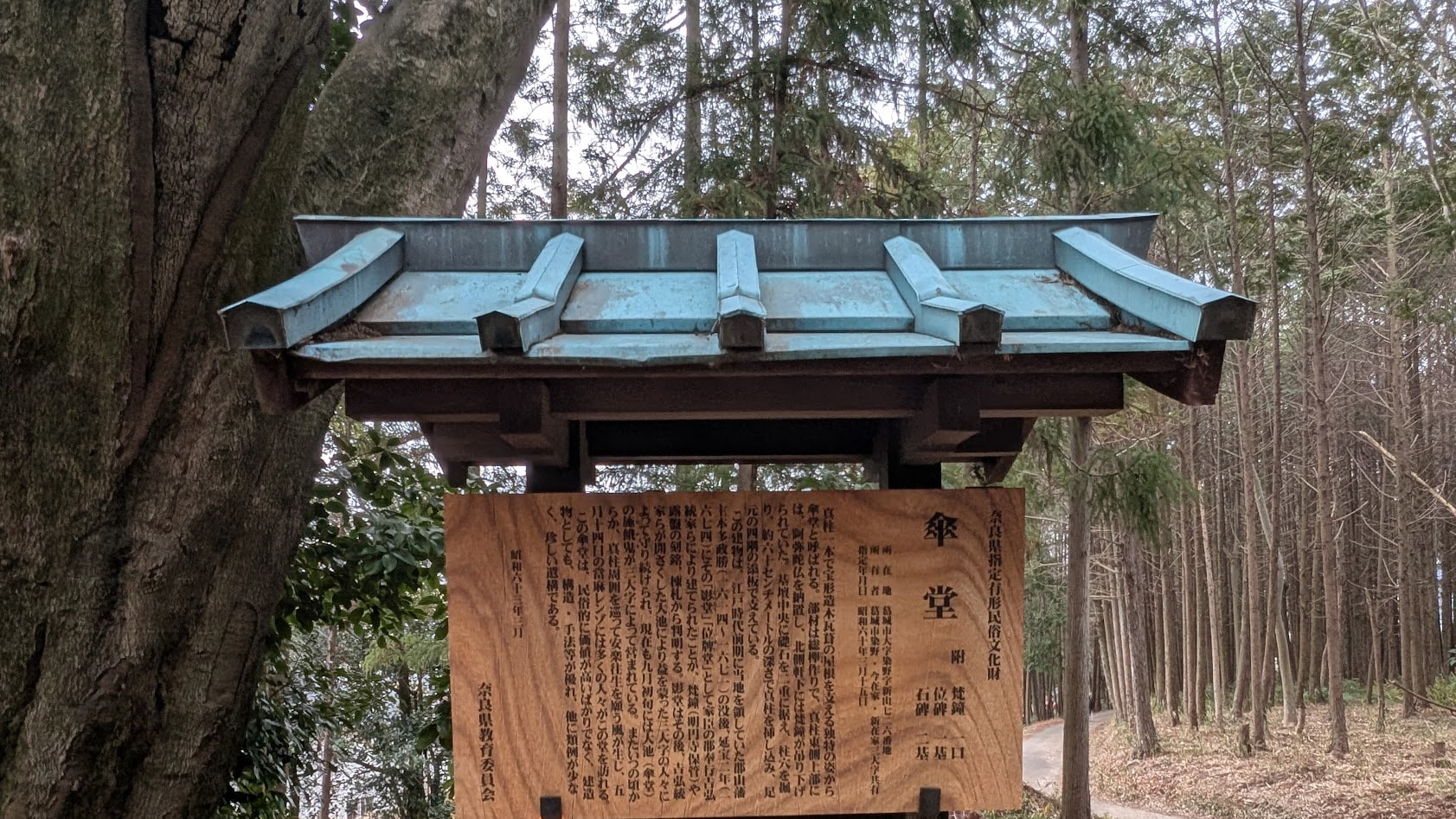 奈良県葛城市にある傘堂の案内板。一本柱の独特な建築様式と、郡山藩主・本多政勝の供養のために建立された由来が記されている