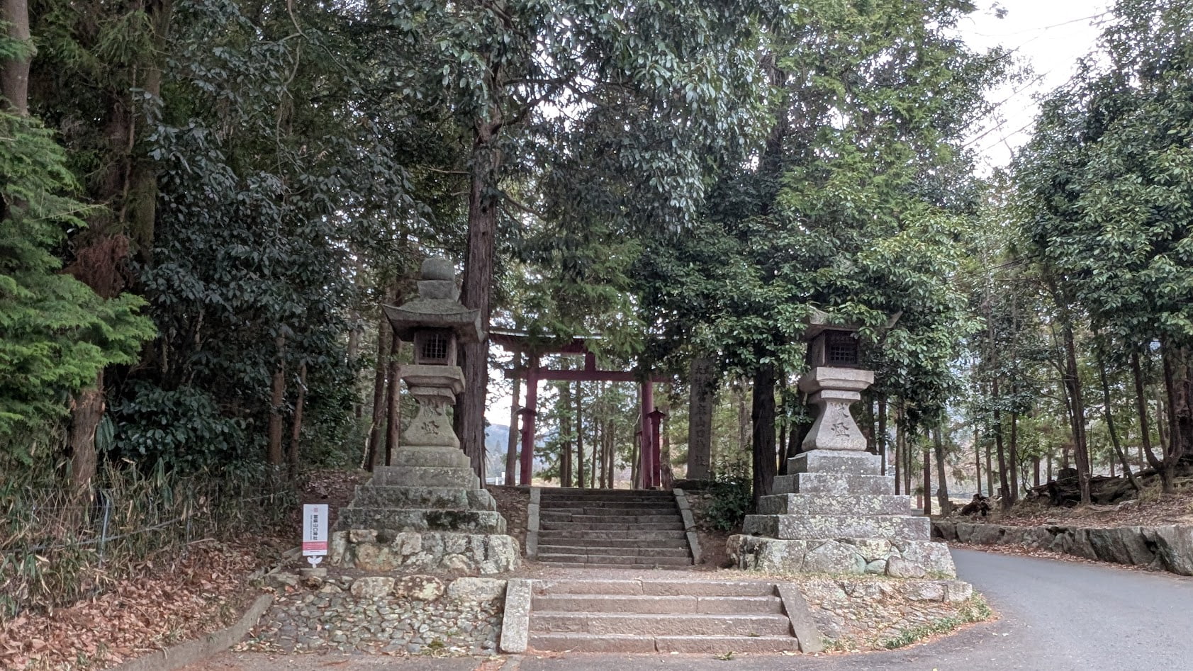 奈良 當麻山口神社の入り口全景。重厚な石の灯篭と鳥居。歴史を感じる社号標が並ぶ、静寂に包まれた神域への入り口