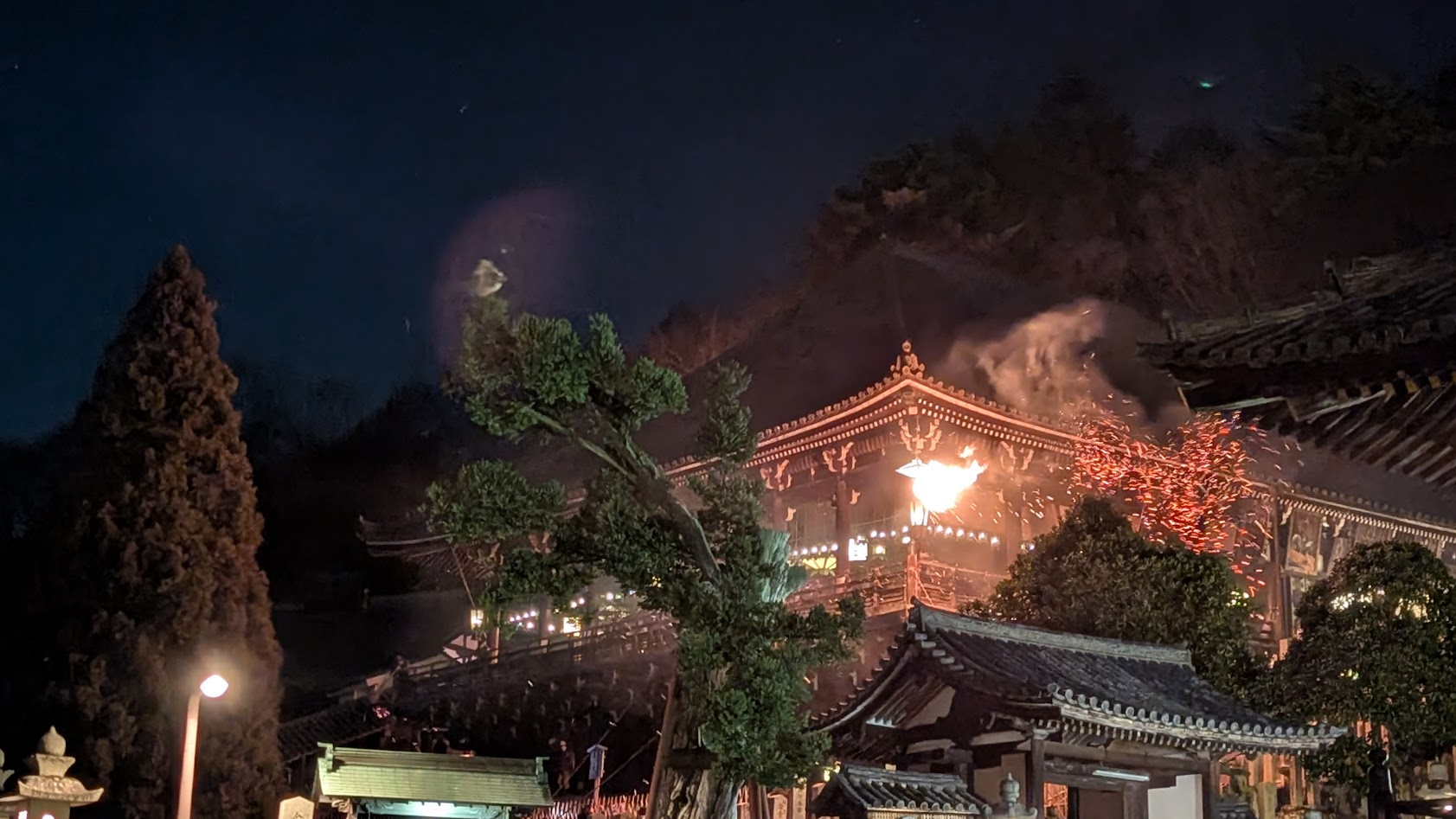 奈良・東大寺二月堂の修二会（お水取り）。松明から吹き出した火の粉が風に煽られ、夜闇を背景に渦を巻いて舞い散る迫力の瞬間。