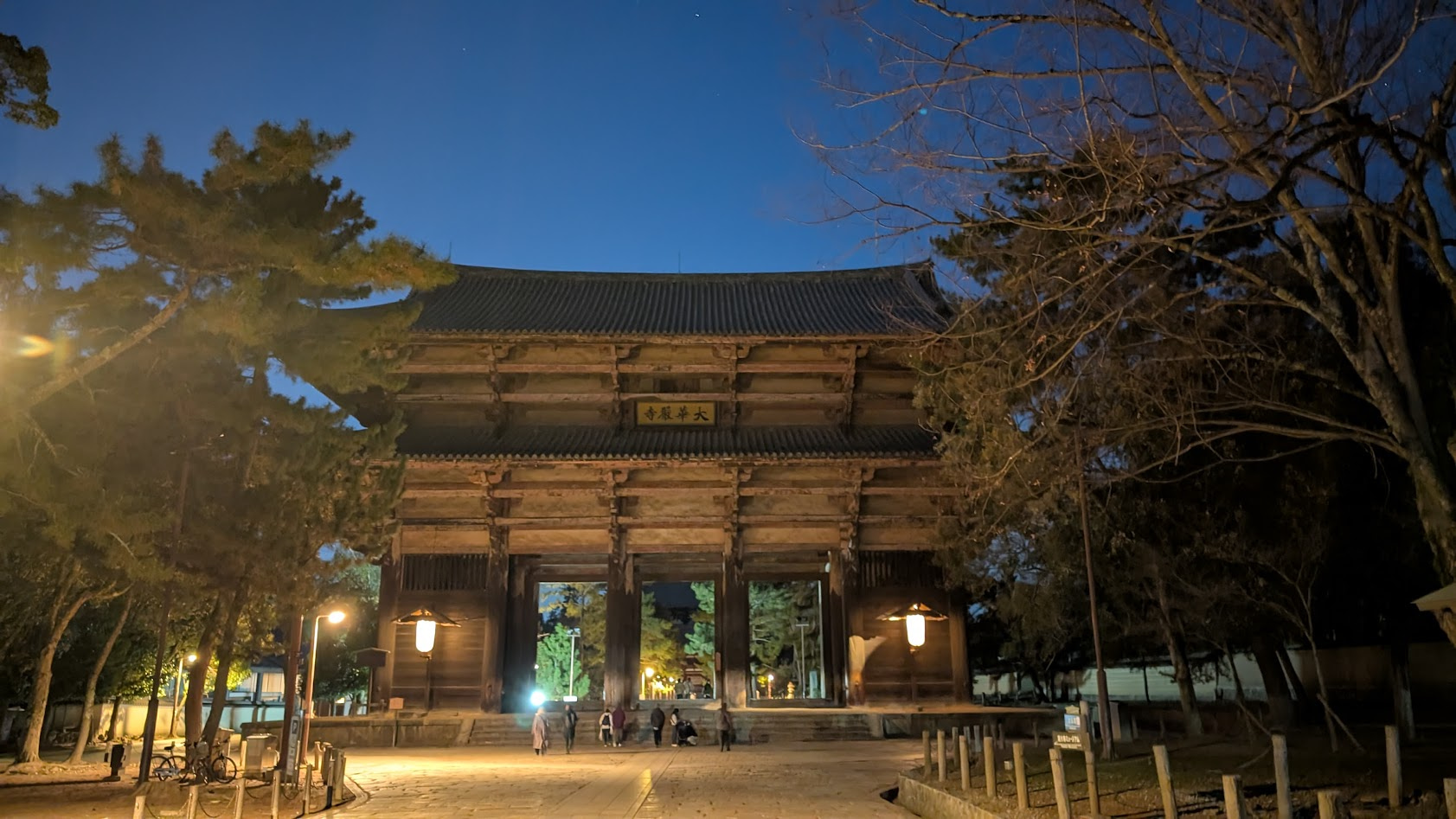 奈良・東大寺の夜の境内。街灯や灯籠の光が石畳をかすかに照らす、静寂に包まれた夜の仁王門（南大門）。