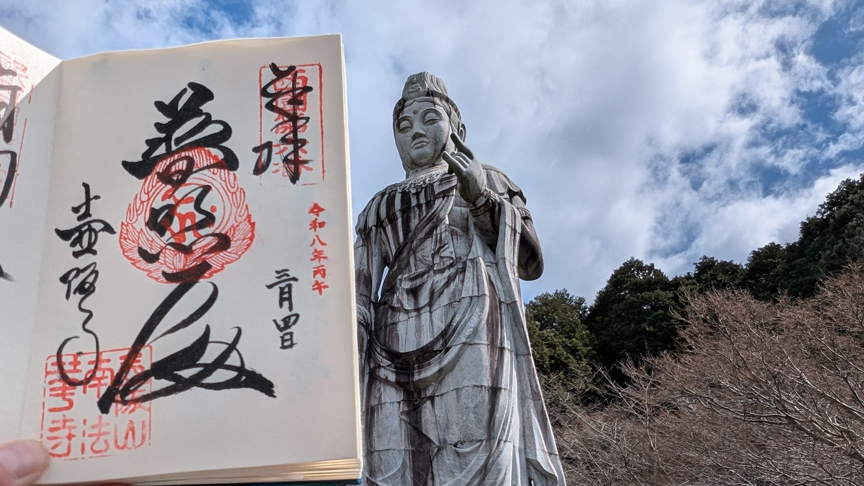 奈良・壷阪寺の高さ20mの大観音石像を背景に、授与された御朱印を並べた光景。