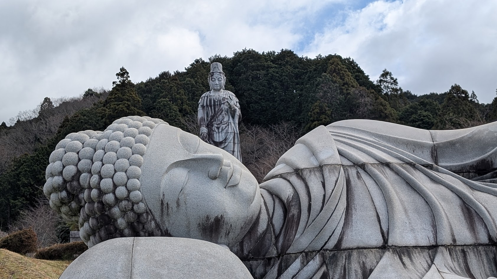 奈良・壷阪寺。全長8メートルの大涅槃石像のお顔アップと、その背後にそびえる高さ20mの大観音石像。