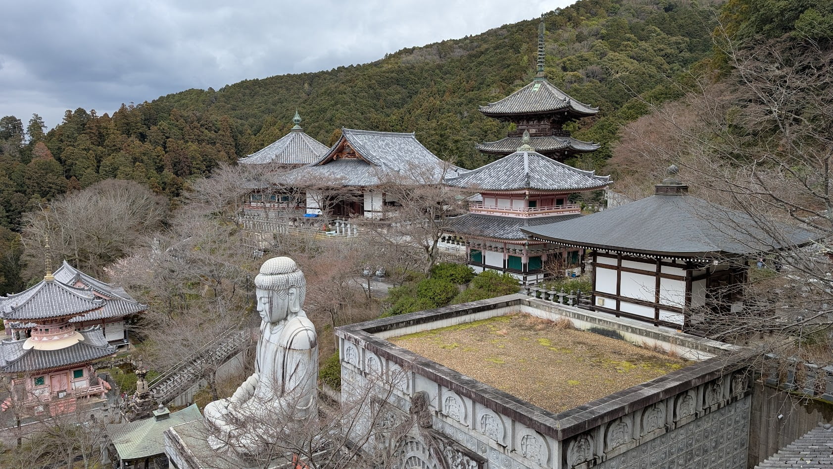 奈良・壷阪寺の高台からの全景。手前に大釈迦如来石像(桜大仏)、奥に三重塔や本堂を望む風景。