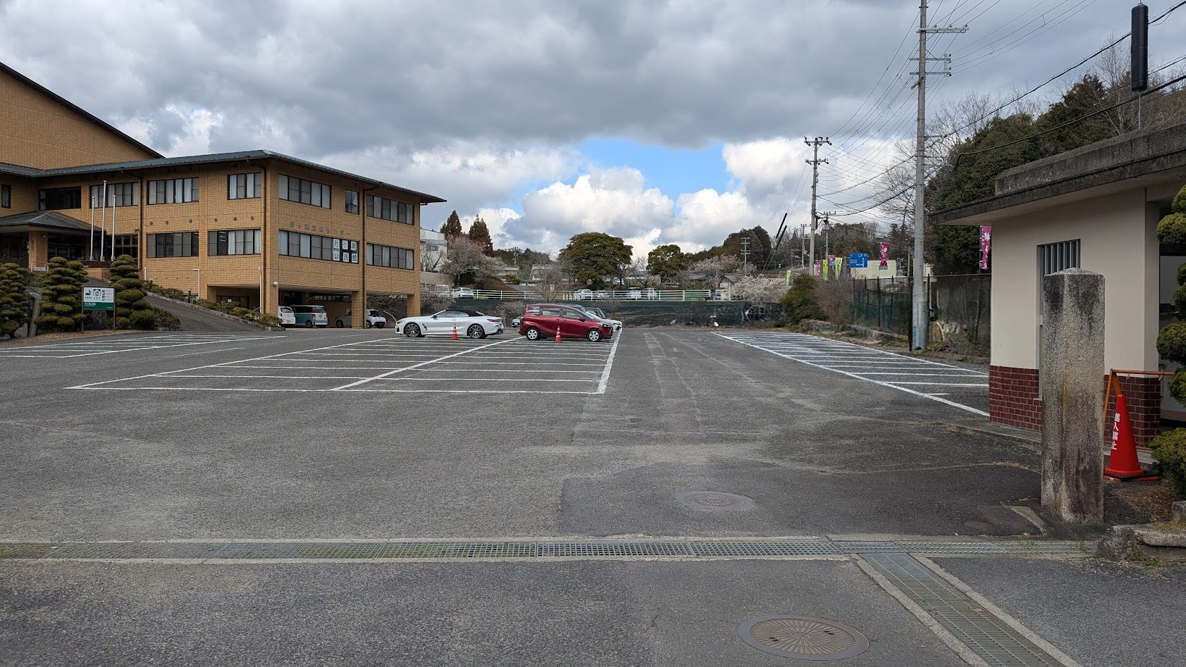 奈良県・月ヶ瀬梅林の散策に最適な、行政センター・公民館・小学校周辺の大規模な舗装駐車場。約70〜80台分の白線区画がある。