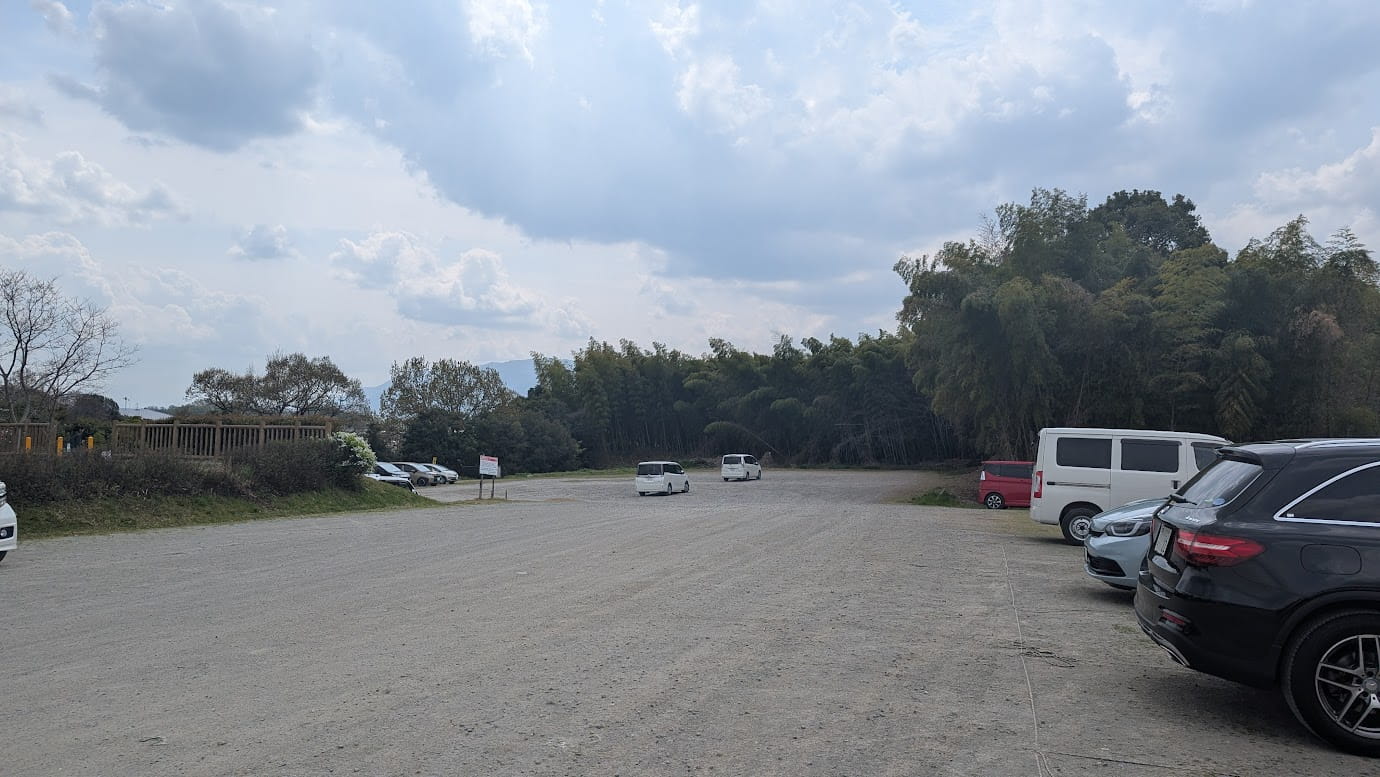 奈良県広陵町の竹取公園にある広大な砂利敷きの駐車場。馬見丘陵公園の混雑時にも対応できる広いスペースがあり、一番奥のエリアは平日昼間でも空きが十分にある様子（2026年3月30日撮影）。