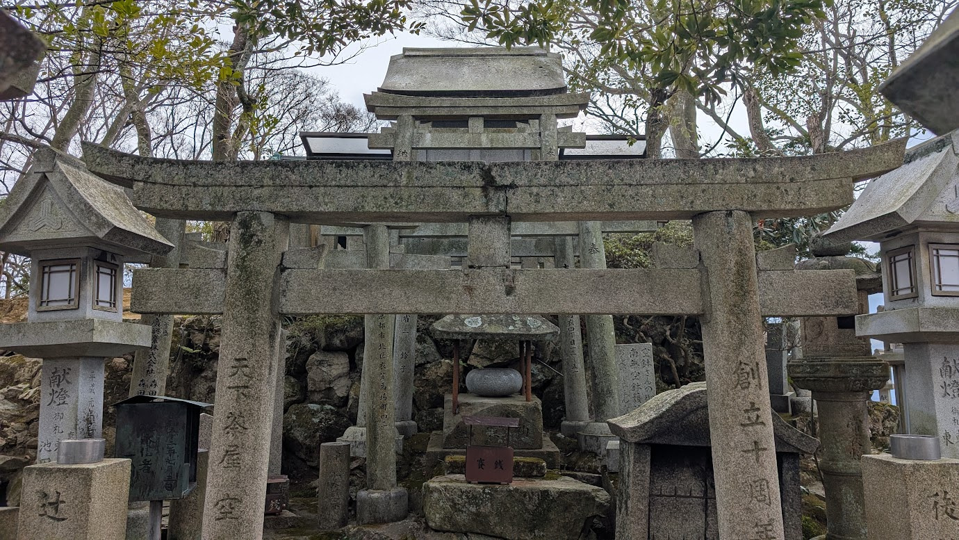 空鉢護法堂の真裏にある聖域。幾重にも重なる石造りの鳥居と、その奥に祀られた「空鉢」を象った石の宝珠。周囲は切り立った石垣と古い石灯籠に囲まれている。