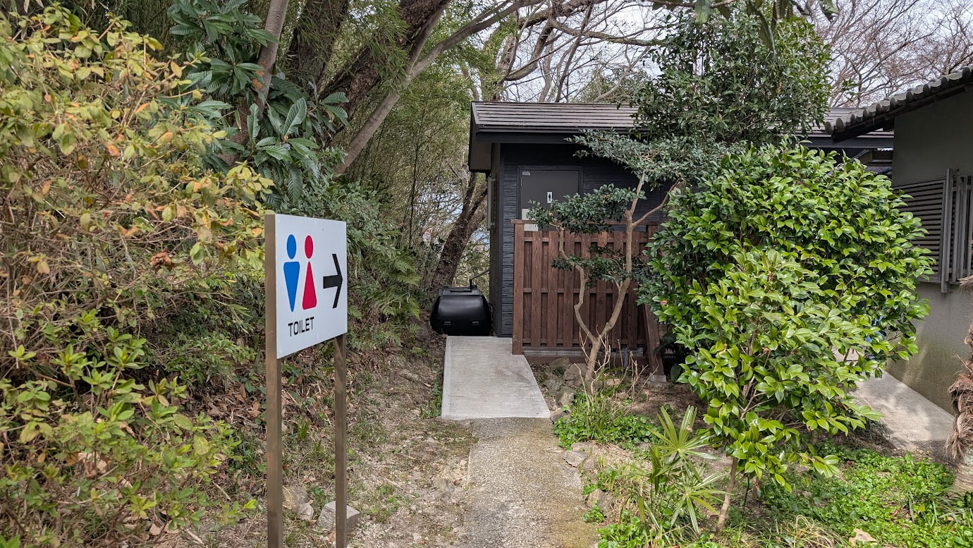 信貴山・空鉢護法堂の山頂付近にある公衆トイレ。木造風の落ち着いた外観で、周囲はきれいに掃除されており、登山者のための休憩スポットのようになっている。