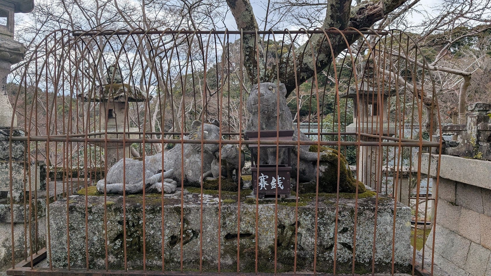 信貴山朝護孫子寺の本堂前にある、二匹の虎の石像。どちらも目を細めて笑っているような表情をしており、周囲は安全のためか金属製の柵(檻)で囲われている。
