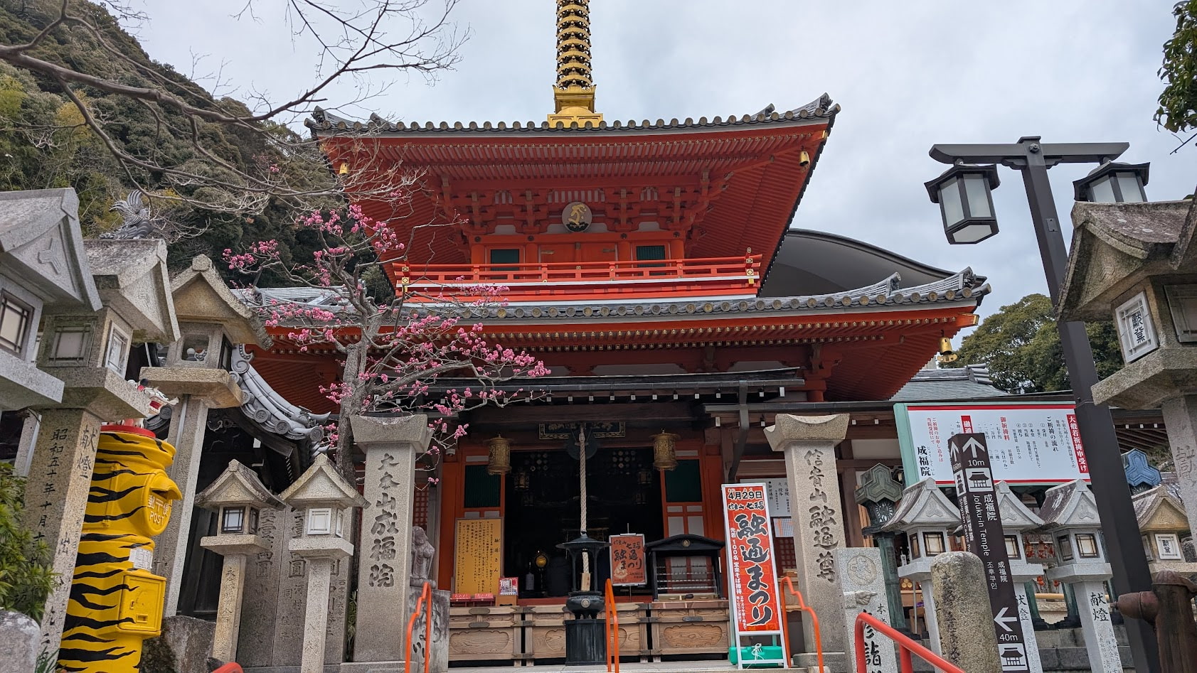 信貴山朝護孫子寺・成福院の境内にある、黄色と黒の虎模様が描かれた珍しい郵便ポスト。背景には成福院の融通堂が見える。