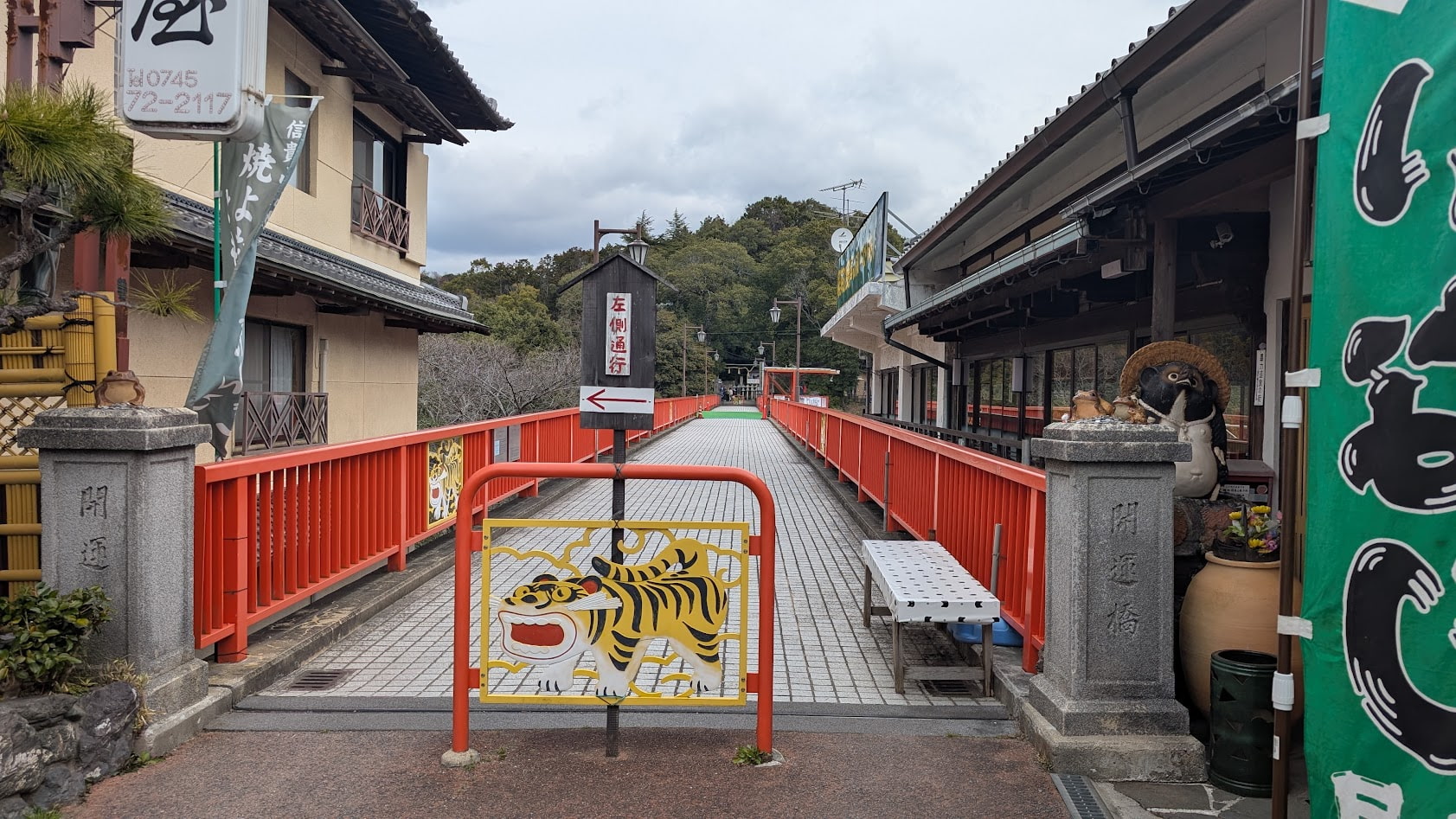 信貴山朝護孫子寺の「開運橋」の入り口。鮮やかな朱色の欄干と、橋手手間へは食堂と奥へと続くまっすぐな橋の道が見える。