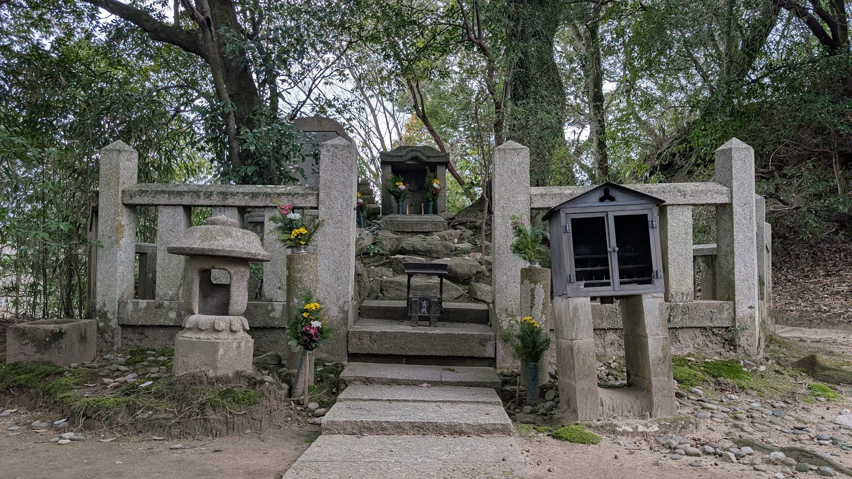 信貴山朝護孫子寺の開山堂奥にある、明蓮聖人の墓所「明蓮塚」。石積みと古い石塔が並び、周囲は高い木々に囲まれた非常に静かなエリア。