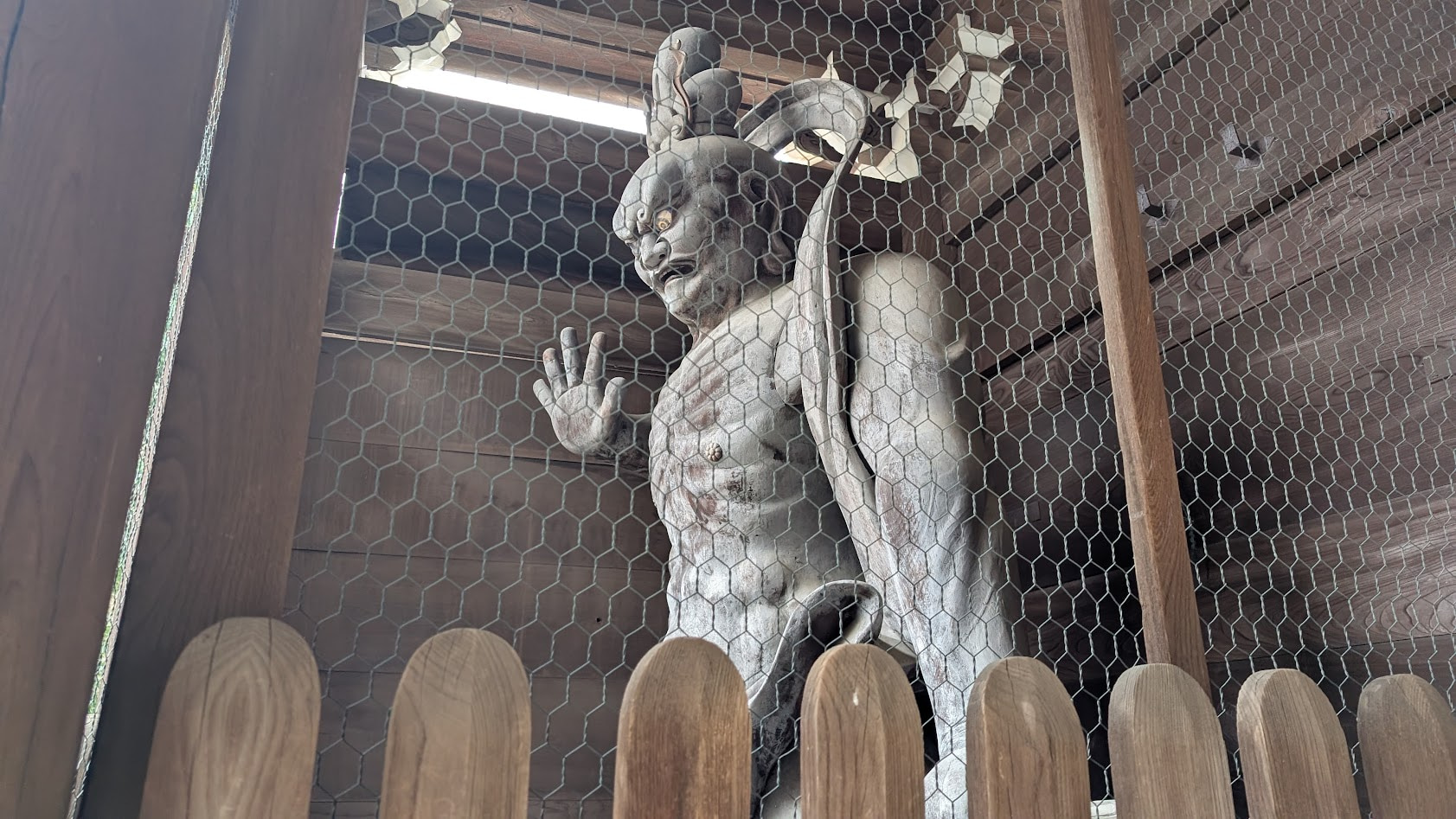 信貴山朝護孫子寺の仁王門に立つ、金剛力士像の阿形(あぎょう)。口を大きく開いた咆哮の表情で、木造の荒々しい質感と力強い筋肉の描写が際立つアップ。