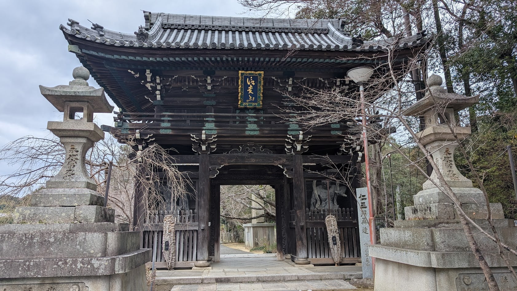 信貴山朝護孫子寺の仁王門。重厚な木造の楼門で、左右に金剛力士像(仁王像)が安置されている。門の奥へと参道が続いている。