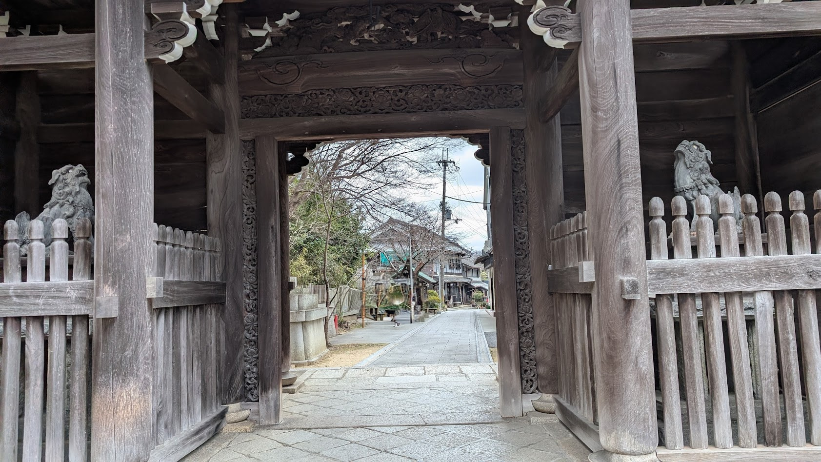 信貴山朝護孫子寺・仁王門の裏側に配置された狛犬の全体像。仁王像の背後に位置し、静かに参道を見守る石造りの狛犬。