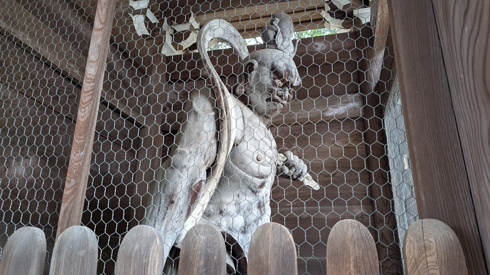 信貴山朝護孫子寺の仁王門に立つ、金剛力士像の吽形(うんぎょう)。口を固く閉じた「吽(うん)」の表情で、木造の静かな質感と威圧的な眼差しが際立つアップ。